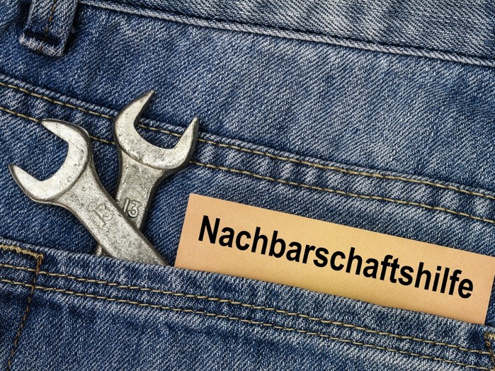 In einer Hosentasche stecken zwei Gabelschlüssel und ein Zettel, auf dem "Nachbarschaftshilfe" steht